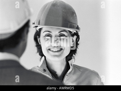 Woman wearing hard hat, smiling, close-up, b&w Stock Photo
