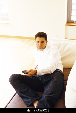 Man lying on sofa with remote control Stock Photo