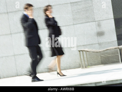 Businessman and woman using cell phones in street, full length, blurred motion Stock Photo