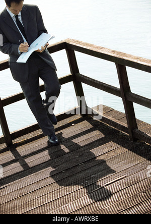 Businessman leaning on railing above water Stock Photo