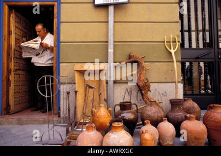 Man reads a newspaper and waits for customers , clay jug on the Rastro flea market . Madrid , Spain , Europe Stock Photo