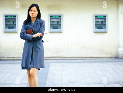 Businesswoman in front of cash machines Stock Photo