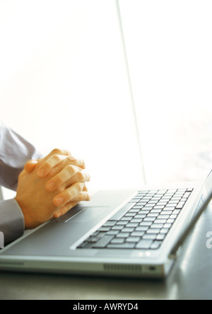 Businessman's folded hands on top of keyboard, close-up Stock Photo