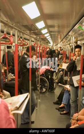 dh Mass Transit Railway MTR HONG KONG Passengers standing in train woman and wheelchair china crowded commuting metro subway commuters Stock Photo