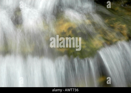 A cascading stream of crystal clear water flowing down a bed of smooth ...