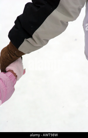 Grandma and Grandchild holding hands while outside playing in the snow while it is snowing Stock Photo