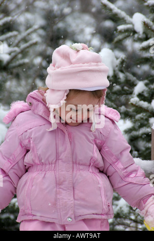 A young girl three years old playing in the snow Stock Photo