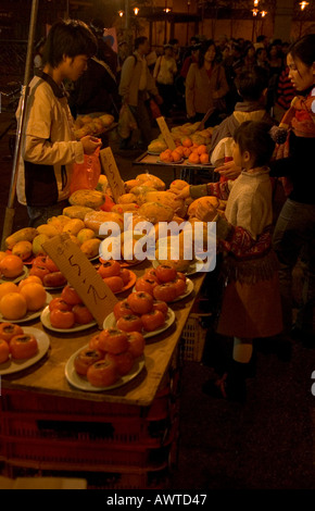 dh Temple street market JORDAN HONG KONG Woman and child at fruit food night market stall yau ma tei Stock Photo