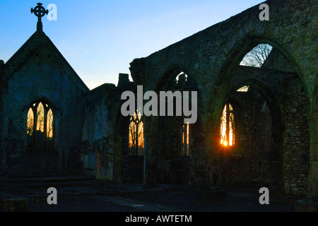 Interior of a burnt out church attacked by arsonists and left as a ruin with a blazing sunrise through the glassless windows Stock Photo