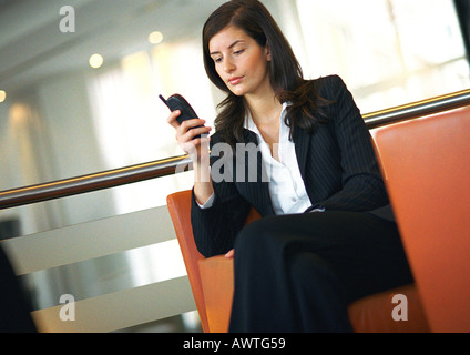 Businesswoman sitting, using cell phone Stock Photo