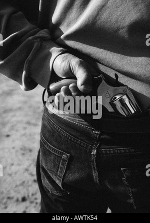 Hand taking gun from back of pants, close-up, b&w Stock Photo