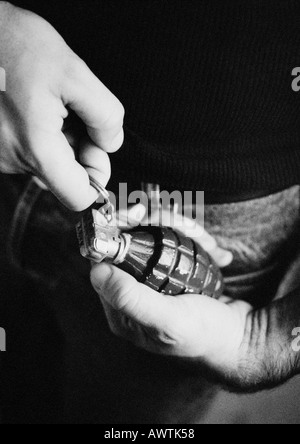 Man taking the pin out of grenade, close-up, b&w Stock Photo