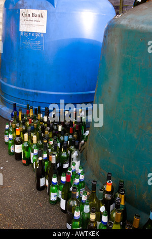 Recycling wine bottles can bank in a large container.  Recycling centre glass bottles facility empty alcohol bottles & festive overfill wheelie bins. Stock Photo