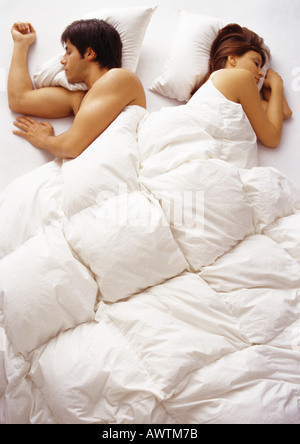 Woman and man lying in bed, facing opposite directions, high angle view Stock Photo