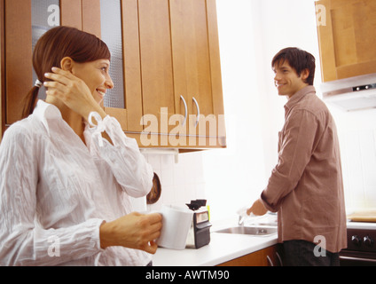 Woman smiling at man washing dishes. Stock Photo