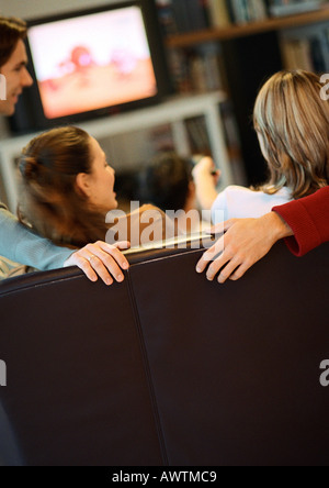 People sitting on couch, talking, rear view, tv in background Stock Photo