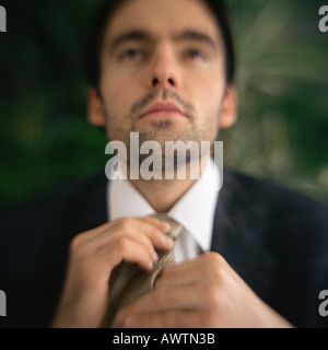 Businessman fixing tie, portrait