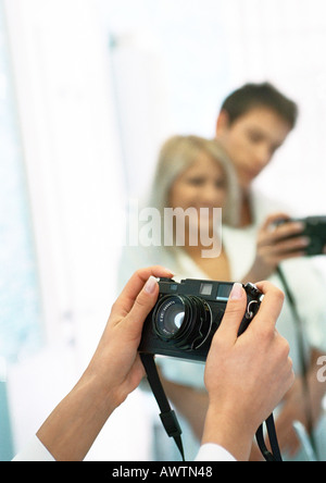Man and woman taking photo of themselves in front of mirror, cropped view Stock Photo