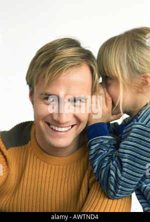 Child, side view, whispering into young man's ear, head and shoulders, close-up Stock Photo
