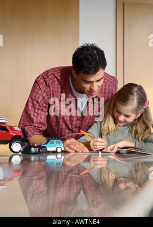 Father looking at what daughter is writing. Stock Photo