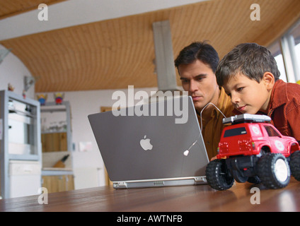 Father and son working on computer together. Stock Photo