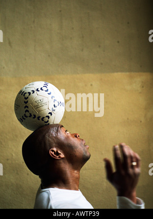 Profile view of man balancing soccer ball on head Stock Photo