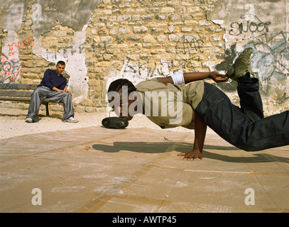 Man balancing on hand, break dancing, man in background sitting on bench Stock Photo