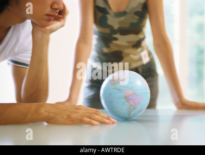 Two people looking at globe on table Stock Photo