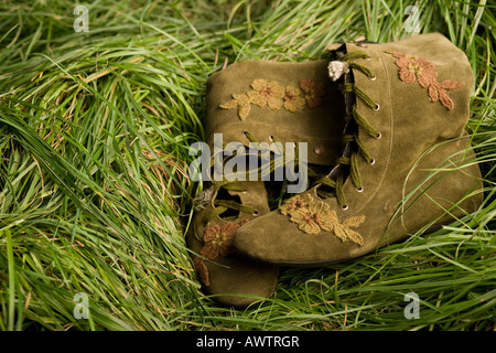 pair of brown leather boots decorated with small flowers placed in green grass Stock Photo