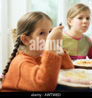 Two girls sitting at table, eating Stock Photo