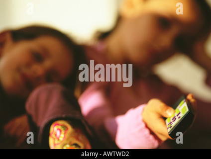 Young boy leaning on young girl's shoulder watching TV, close up, blurred Stock Photo