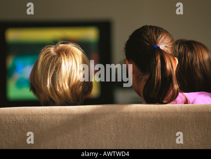 Young boys and girl sitting on couch watching TV, rear view Stock Photo