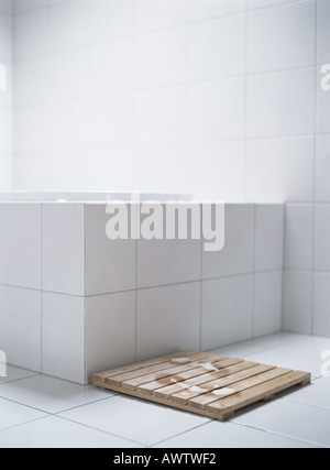 Wet footprints on wooden mat next to bath tub Stock Photo