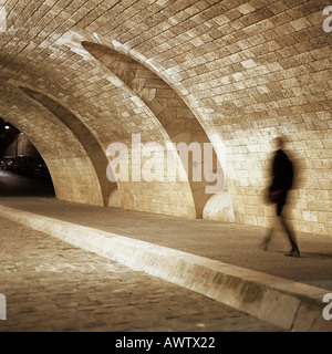 Person walking through tunnel at night