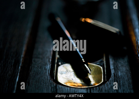Old wooden school desk with a ink well and fountain pen lit by candlelight. Cumbria, UK Stock Photo