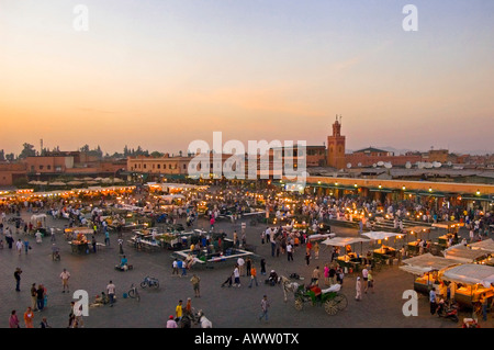 Horizontal cityscape of the hustle and bustle in the main market square Place Jemaa el Fna, Marrakesh at sunset. Stock Photo