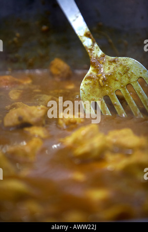 metal spatula used to stir a cooking bowl of chicken curry Stock Photo