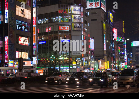 Busy street scene at night with many bright glowing signs on buildings along Yasukuni Dori in Shinjuku Tokyo Japan Stock Photo