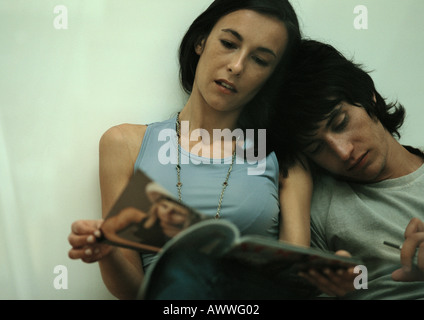 Man leaning head against woman reading magazine Stock Photo