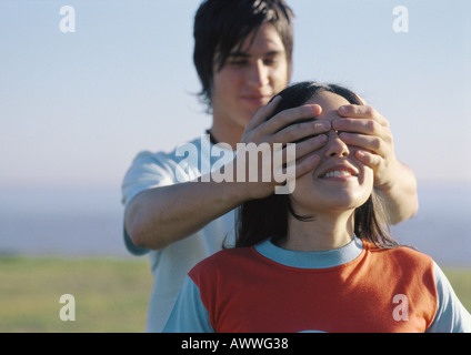 Man putting hands over woman's eyes Stock Photo