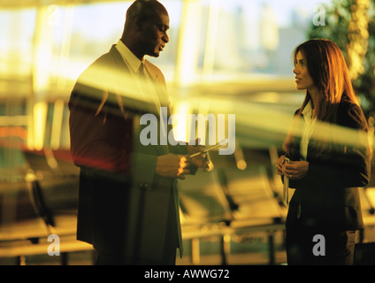Businessman and businesswoman talking in airport terminal. Stock Photo
