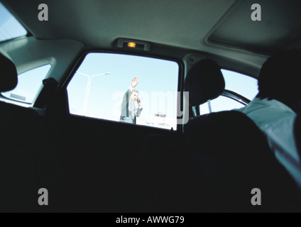 Businessman seen through taxi car window waving hand, hailing taxi car. Stock Photo