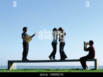 Young people playing on bench near water Stock Photo