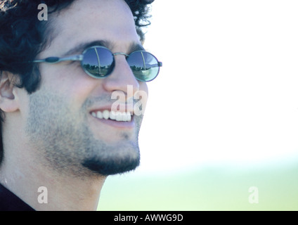 Man wearing sunglasses, smiling, side view, close-up Stock Photo