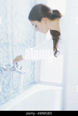 Woman turning bath faucet, blurred Stock Photo