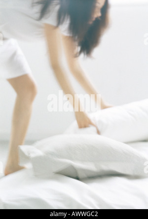 Woman bending over, picking up pillows, blurred Stock Photo