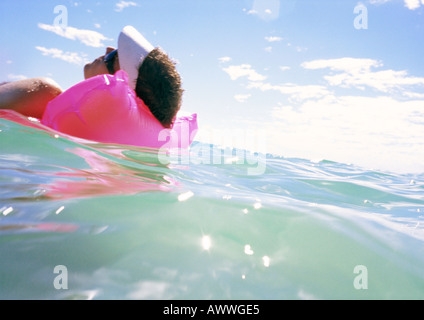 Man floating on air mattress in sea, close-up Stock Photo