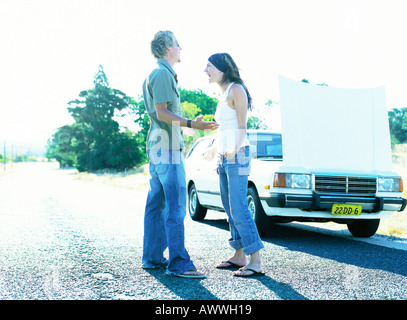 Man and woman standing in front of car with open hood Stock Photo