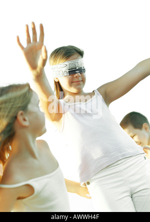 Three children, one blindfolded with arms out Stock Photo