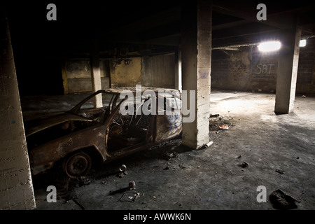 A burnt-out car abandoned in a council flats basement (France). Carcasse de voiture calcinée dans le sous-sol d'une HLM - France Stock Photo
